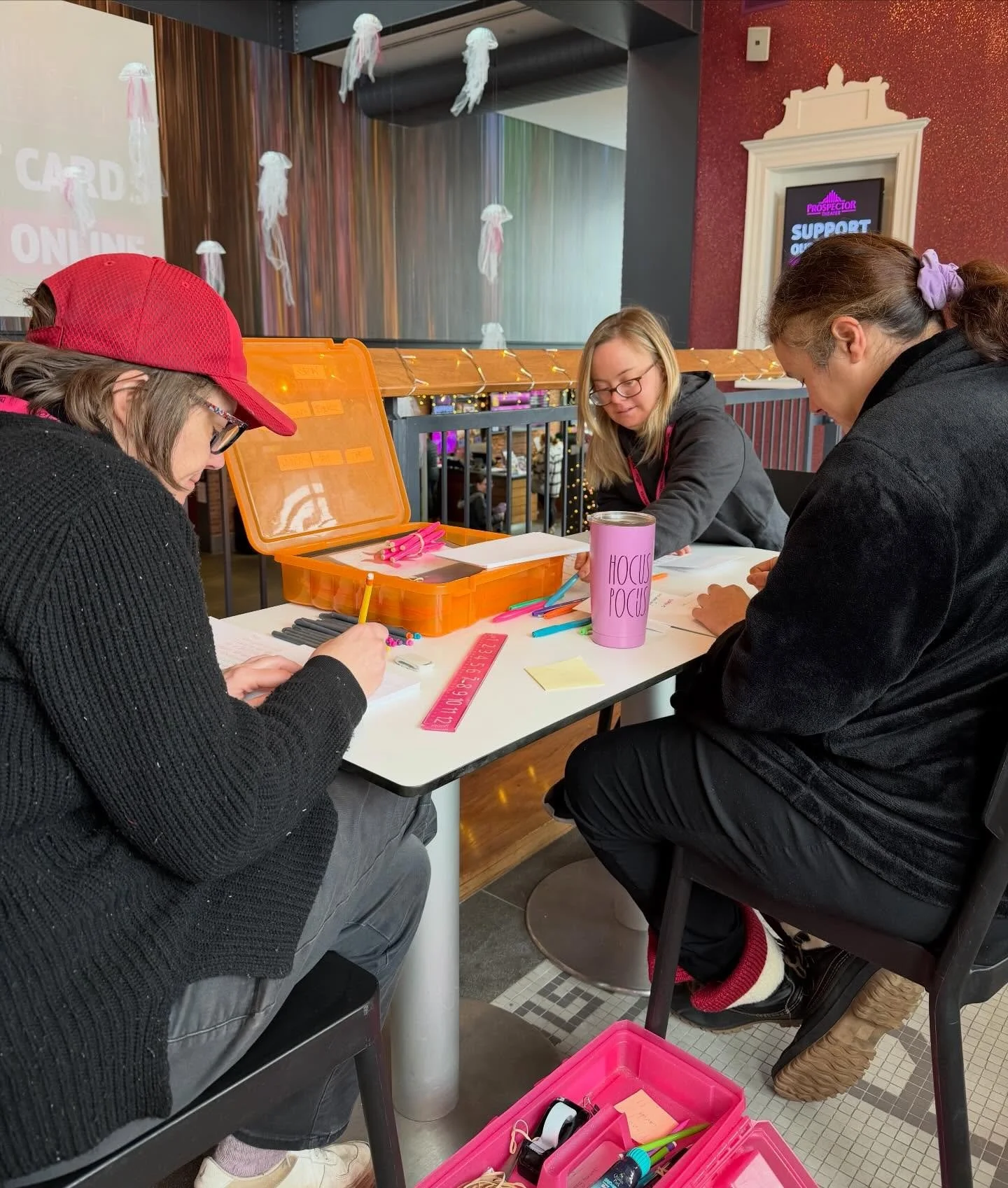 Kathy, Jenny, and Alex are creating personalized, handwritten thank you cards for guests who purchased private theater rentals! ✨💖
.
.
.
.
Photo Caption: Kathy, Jenny, and Alex are seated at a table in the mezzanine in The Prospector. An orange penc