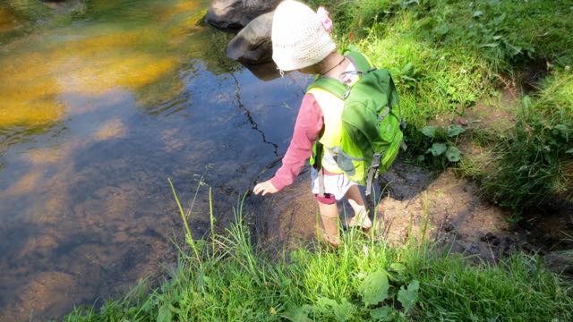 Shoes off, the river is waiting. There are stories about beings that live in the river. Long strands of river grass wave back and forth in the water, these creatures’ hair, perhaps? The children are able to immediately explore it, excited, without pausing to take off their backpacks. In they go.