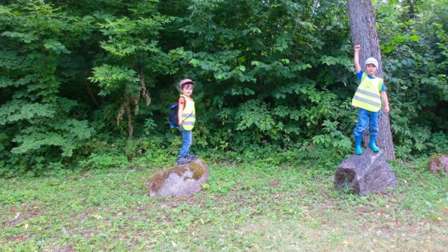 Standing on a circle of rocks, each child becomes the thing or person they imagine. The first is a mustachioed person (the mustache is blade of grass she is holding just so) and then the two are warriors calling out their superpowers.