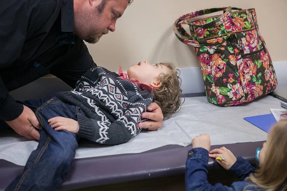  Jaxson's dad, Billy Huffman, gently lays him on the medical exam table before the head neurologist in the study at Cook Children's in Ft. Worth, Texas examines him.&nbsp;He can't hold himself upright or speak and his food must be pureed.&nbsp;      