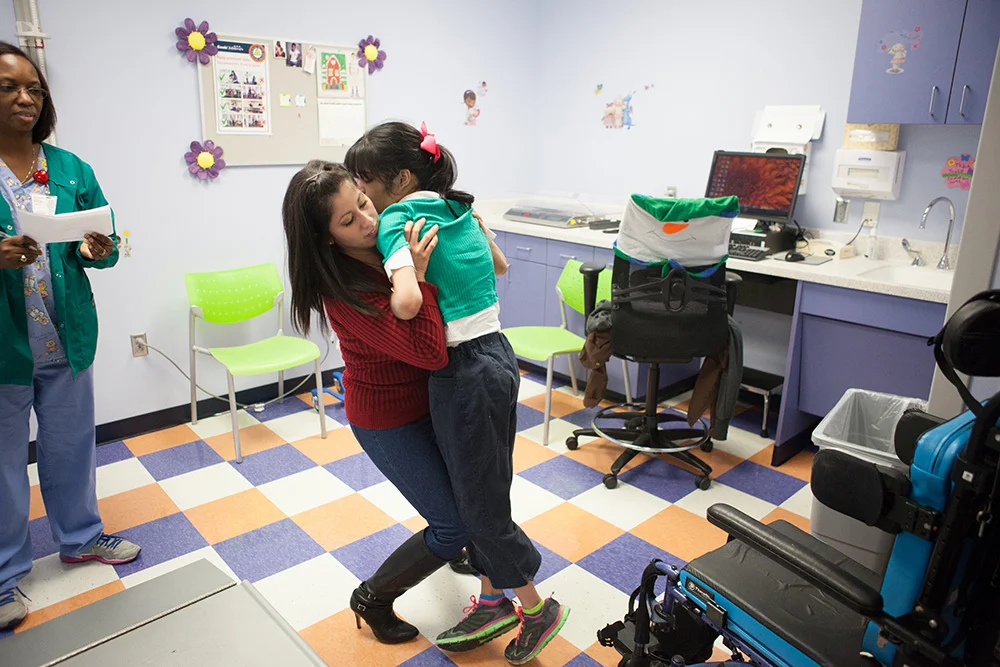  Vanessa lifts and guides her daughter Jordyn, who is almost as tall as she, out of her wheelchair to the scale to weigh her to make sure any weight changes are accounted for in the dosage. December 14, 2015. 