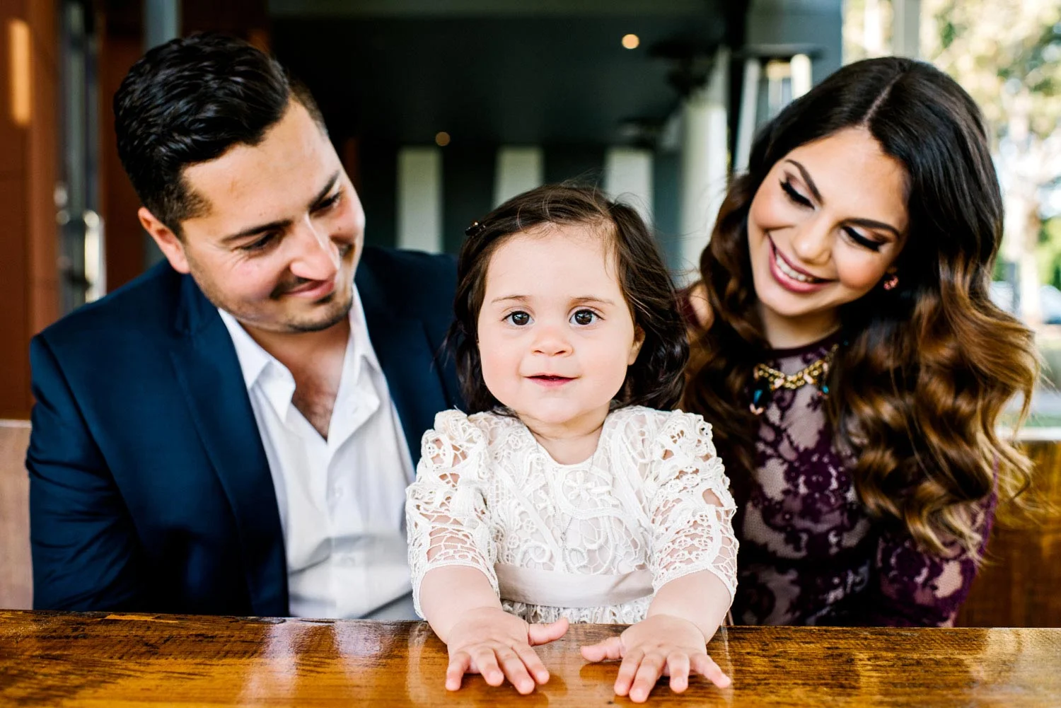 Baby girl with parents in her lace christening gown