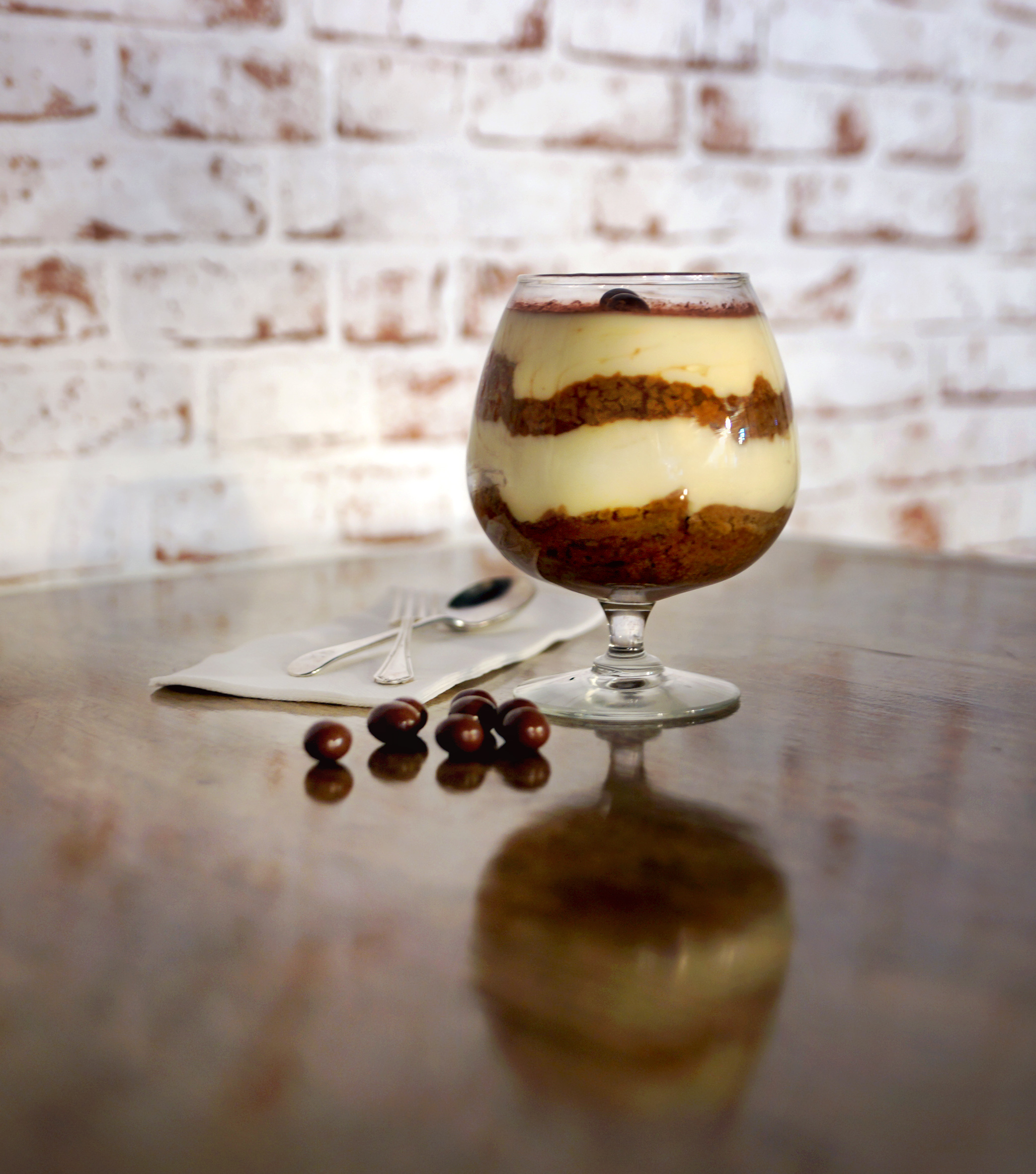 Tiramisu on a wood table with brick wall in the background