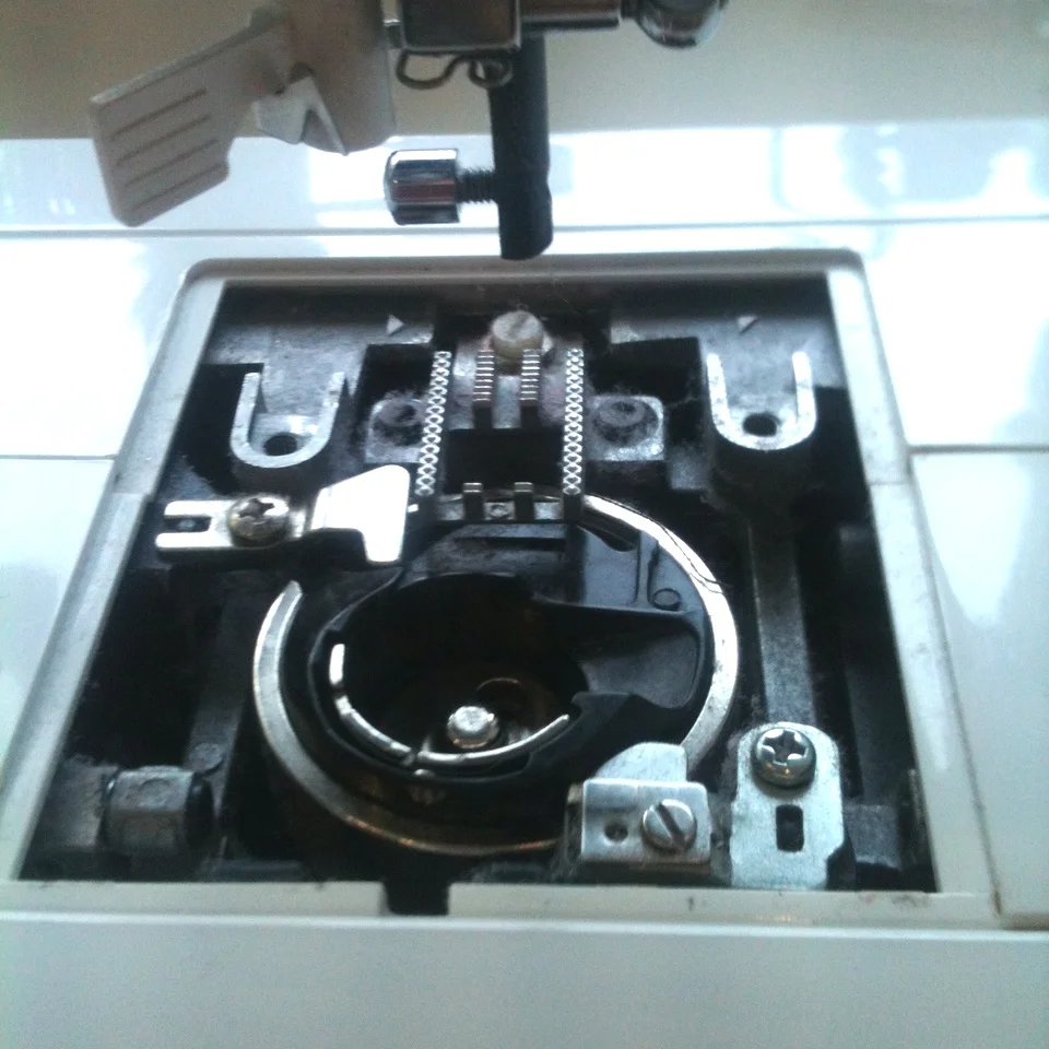 4) This is what it looks like inside. Pretty dusty! Oooops! We'll get to that in a moment. But first you will need to remove the bobbin case from the machine as lots of dust gathers underneath it.