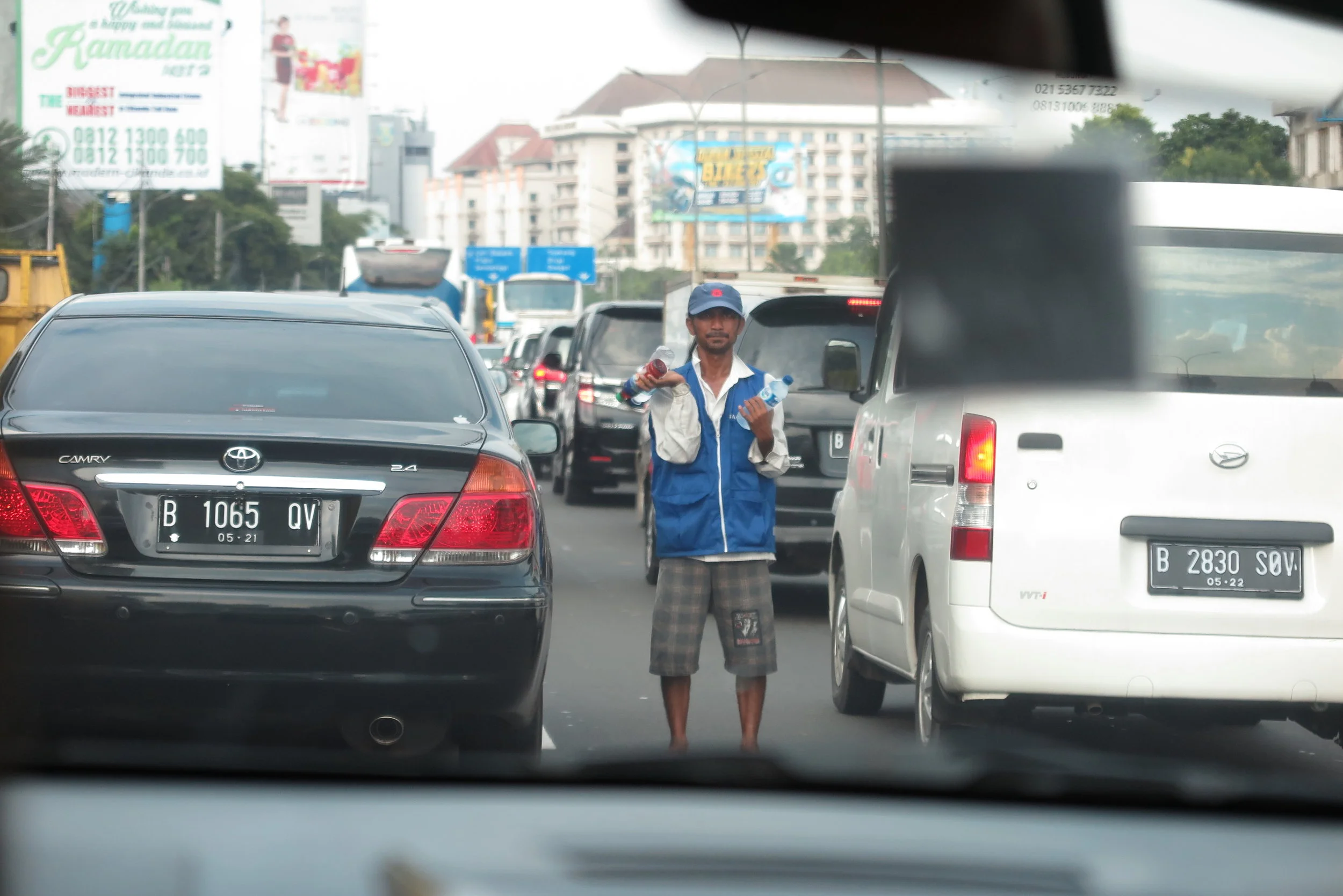 A guy selling water in heavy traffic in Jakarta. The cars are going so slowly that people sell all sorts of stuff by standing in the middle of the highway.