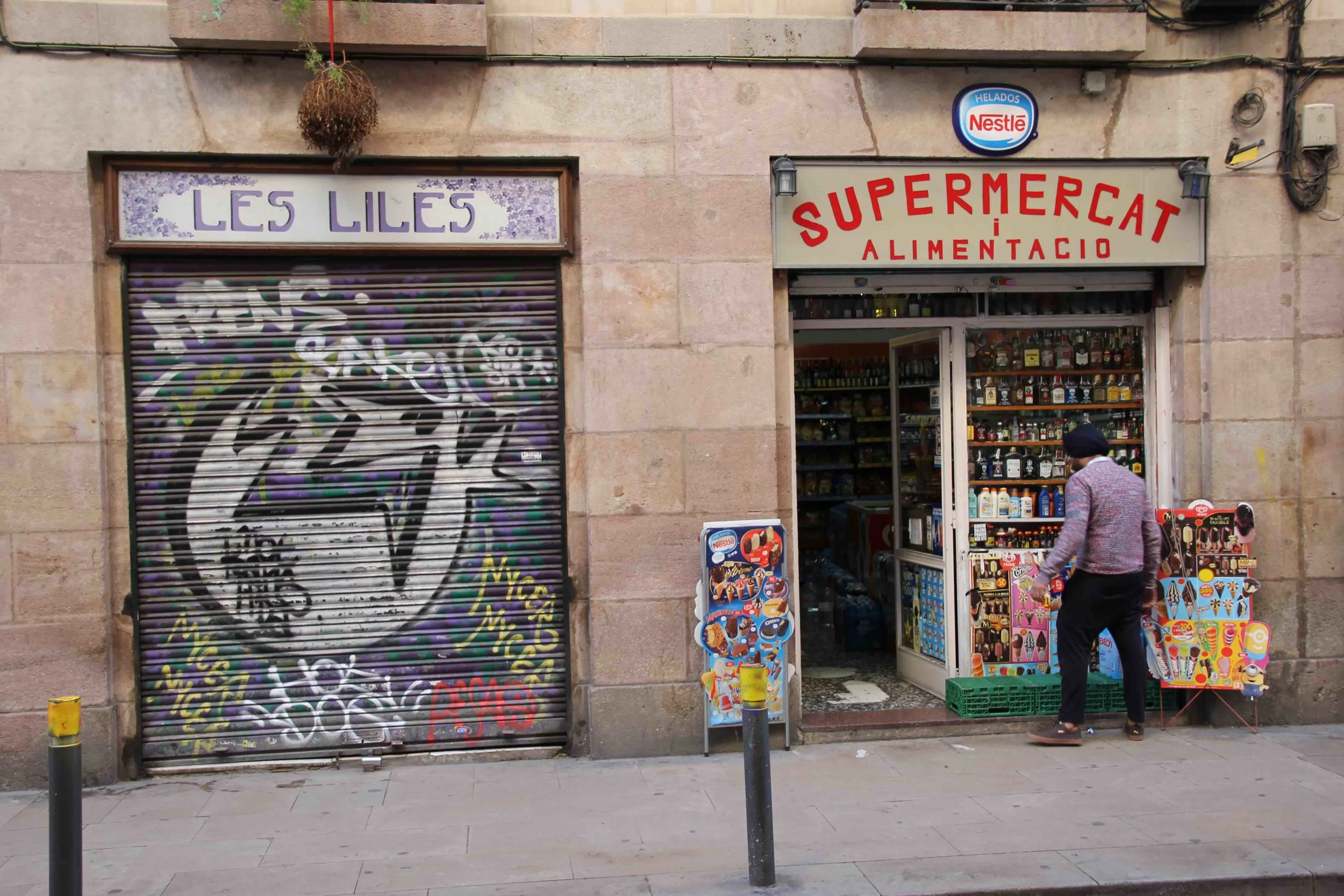 A supermercat in Barcelona run by a Sikh, and next to it a work of graffiti on the shutter of the shop which is very typical of Barcelona street art.