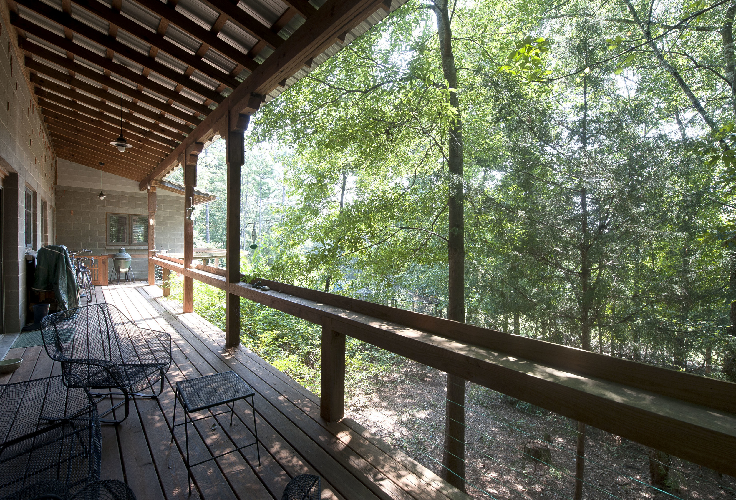 Covered back porch has a beautiful view of woods.