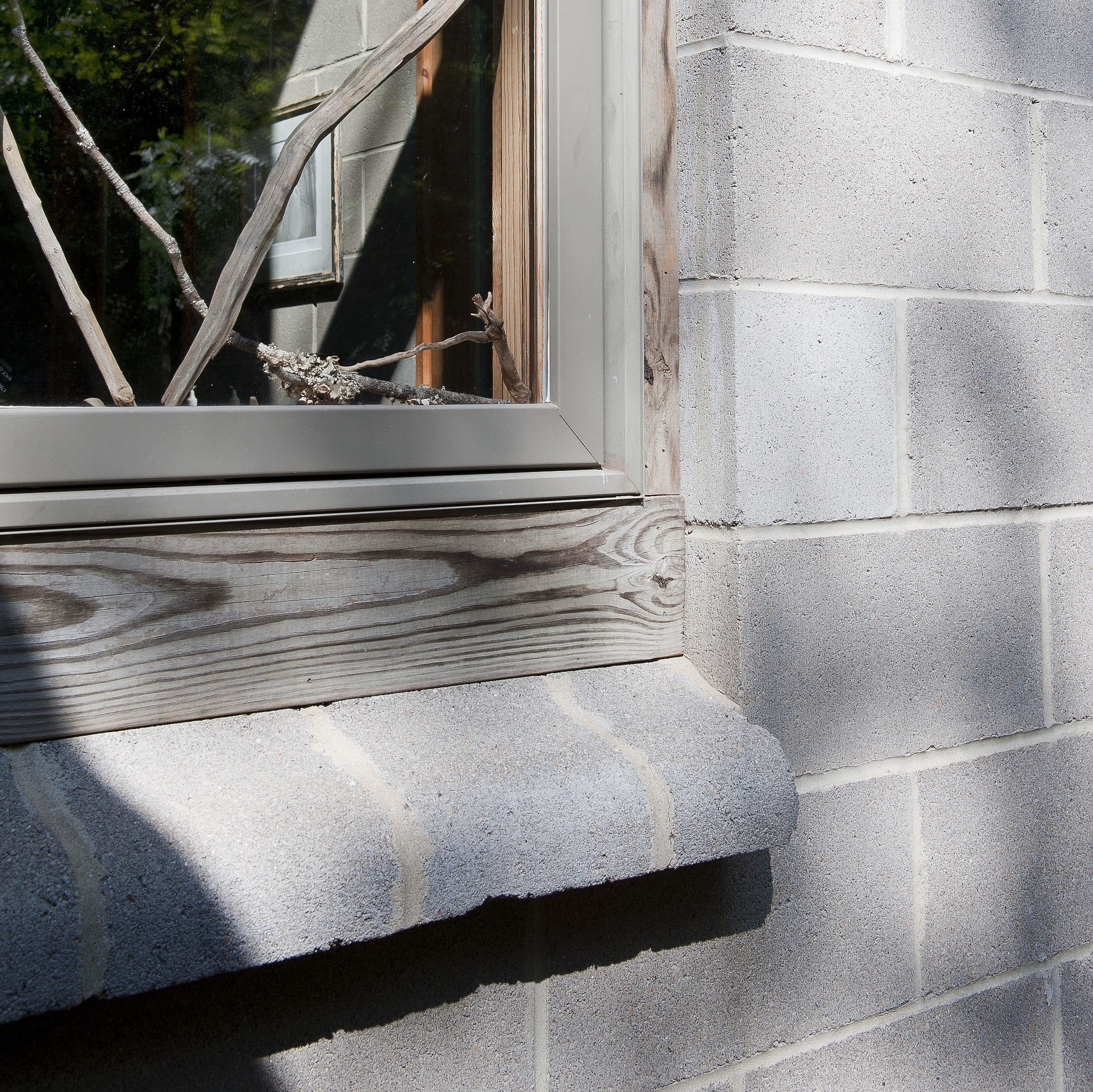 Custom concrete block windowsill enhances natural wood frame.