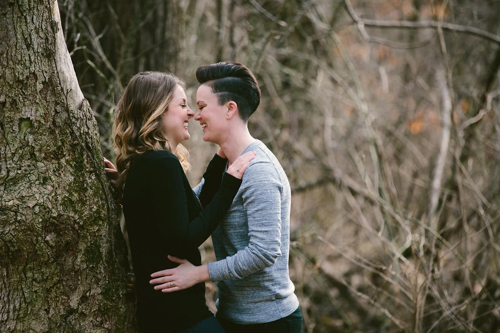 couple leaning against tree laughing