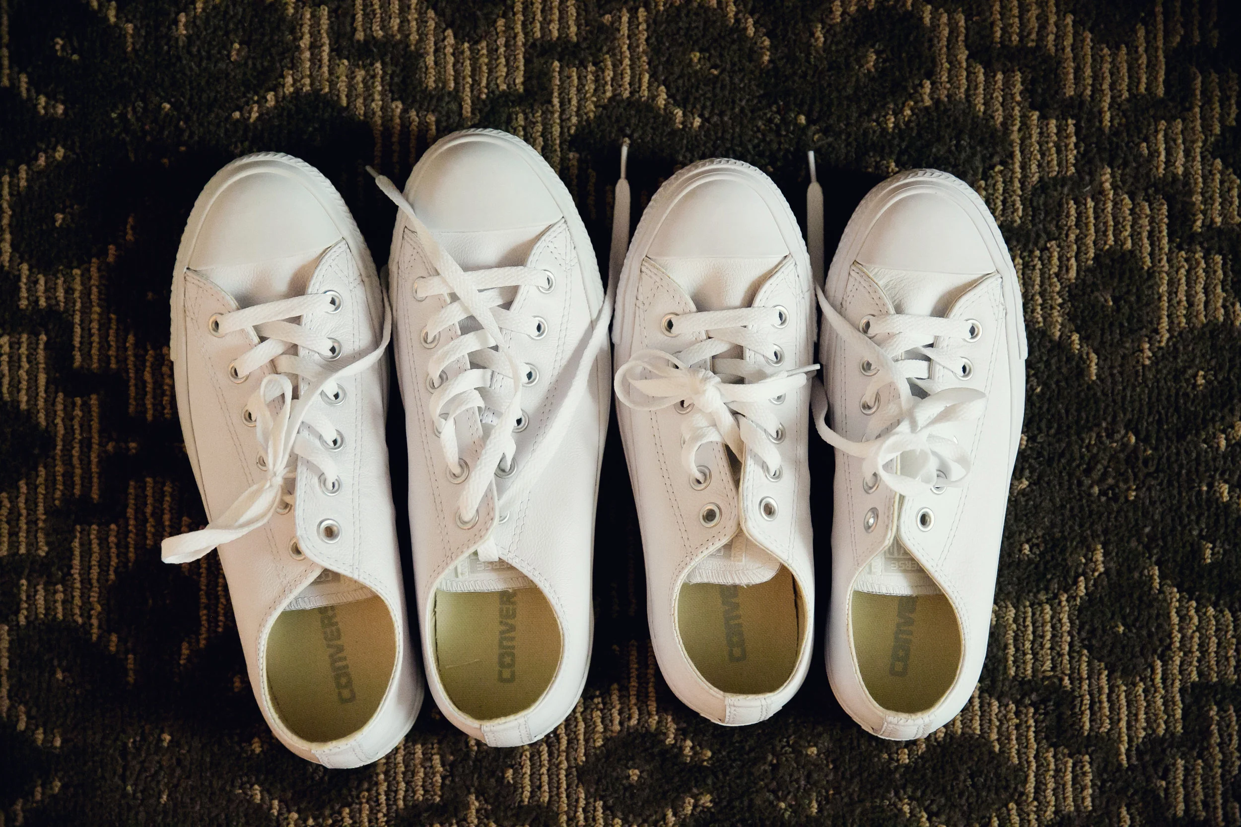 Two pairs of white Converse shoes side by side