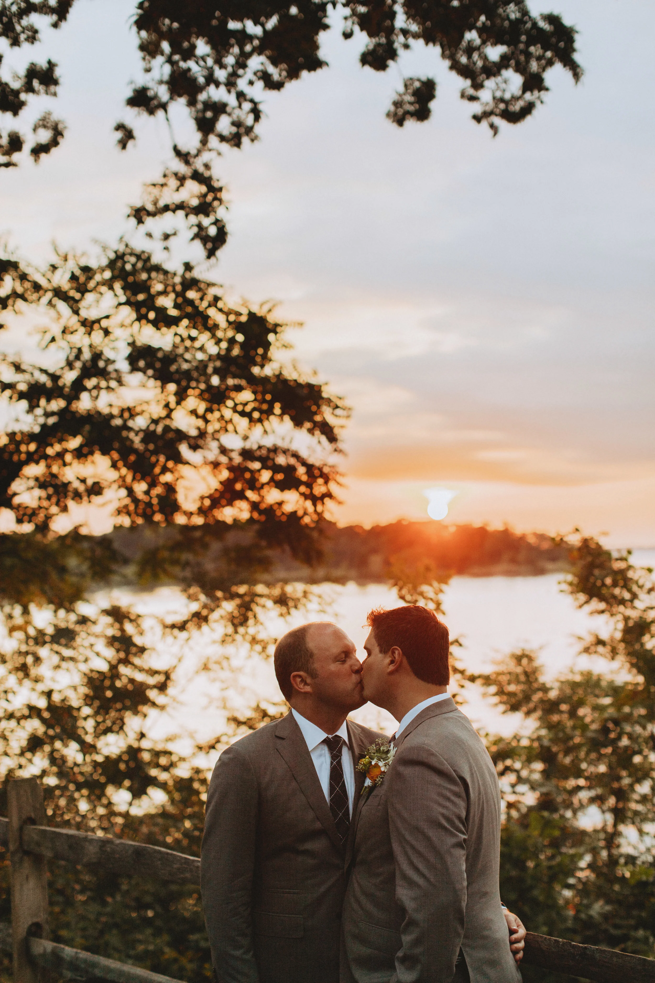 two grooms kissing at sunset