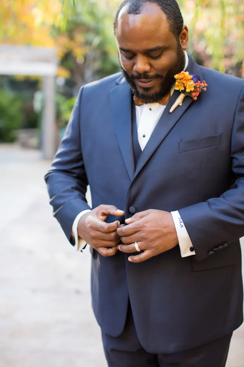 Black groom buttoning his suit