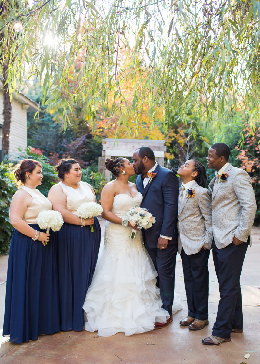 Entire wedding party, with couple kissing