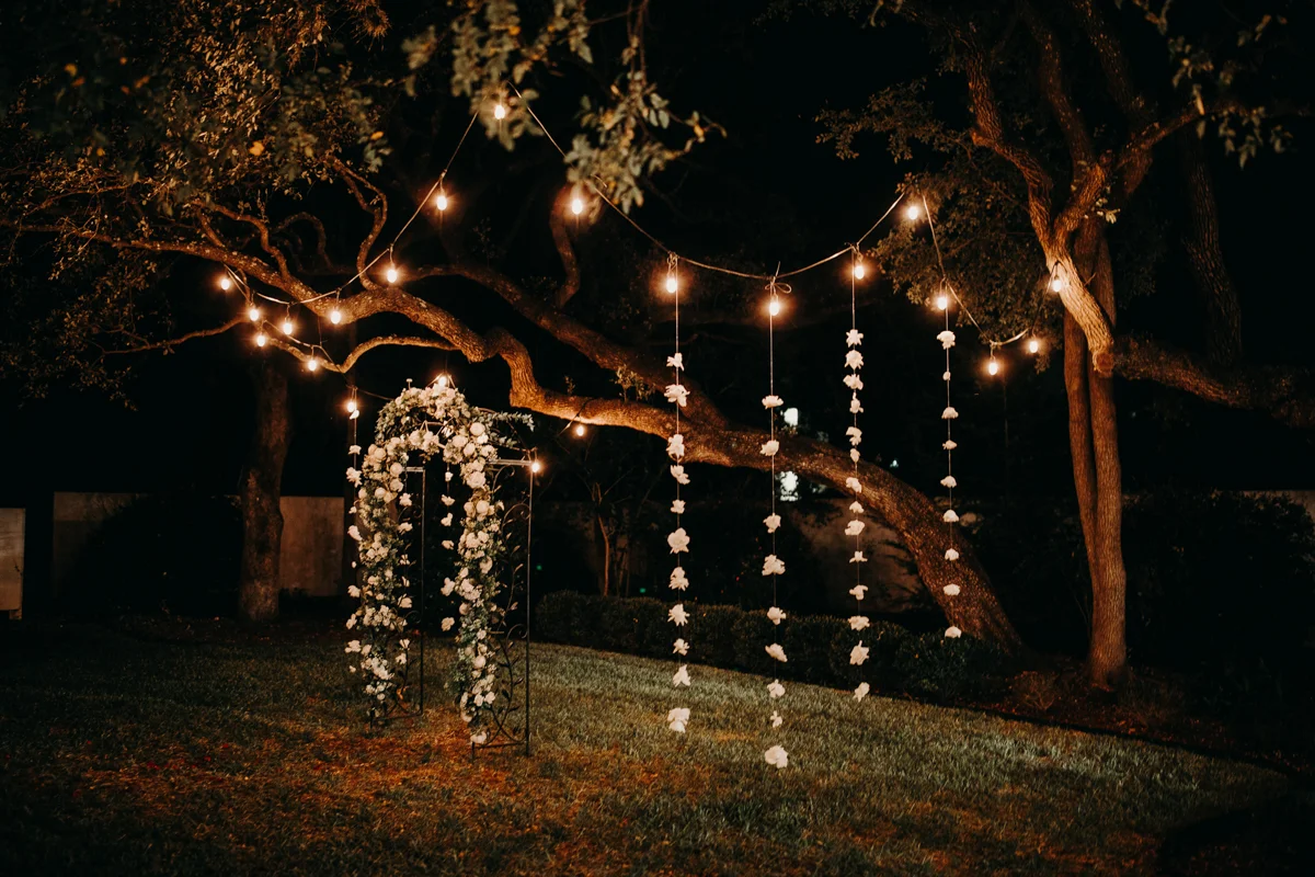 San antonio garden wedding flower arch and string lights on trees at night