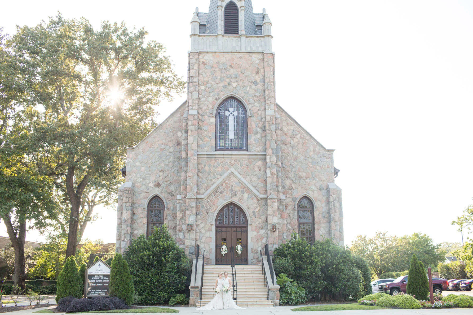 Brides posing together in front of a stone church Jessica Hunt Photography Southeast US Weddings
