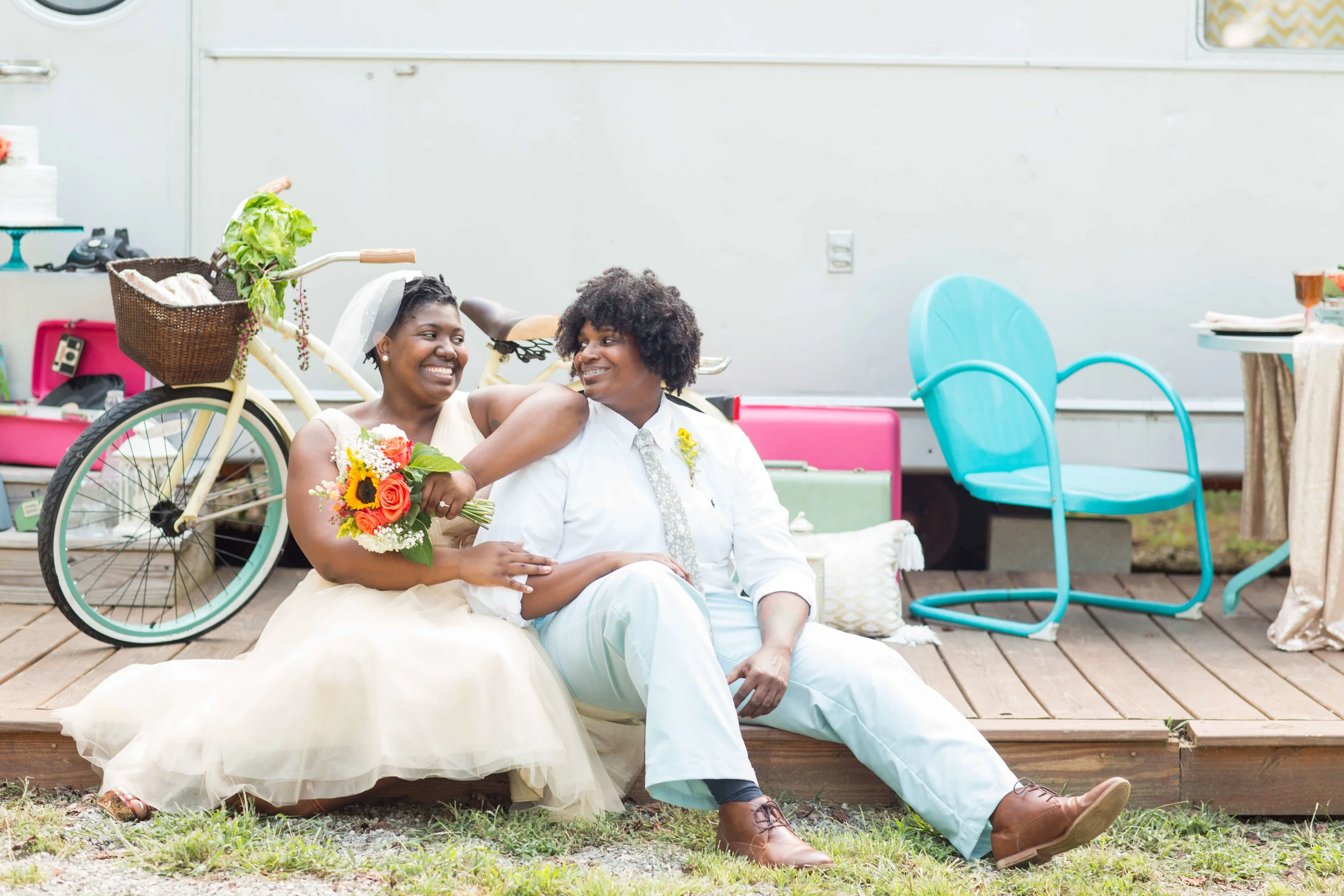 LGBTQ newlywed couple sitting together outside with wedding decor Jessica Hunt Photography Southeast US Weddings
