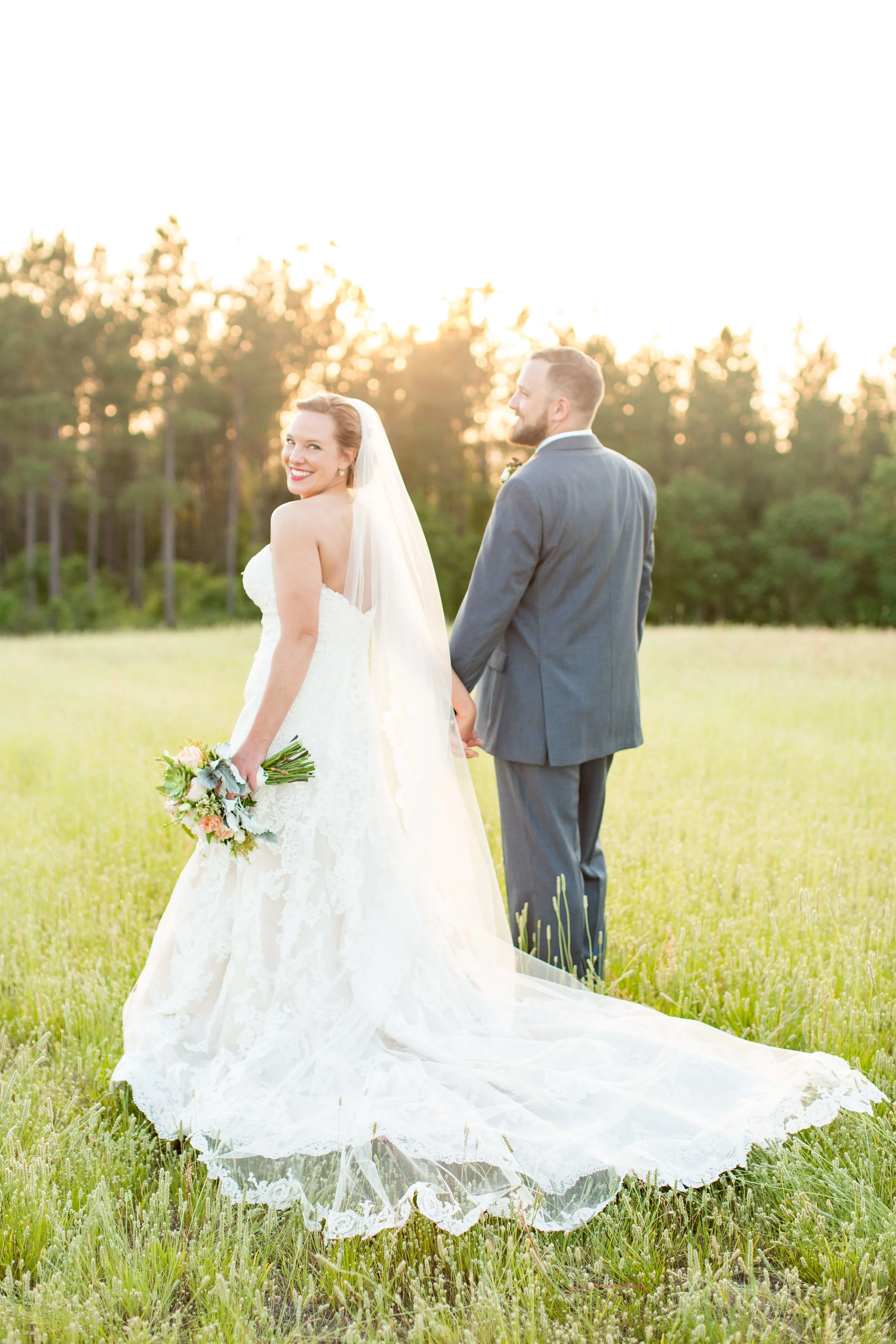 Newlywed couple posing together in a big grassy field Jessica Hunt Photography Southeast US Weddings
