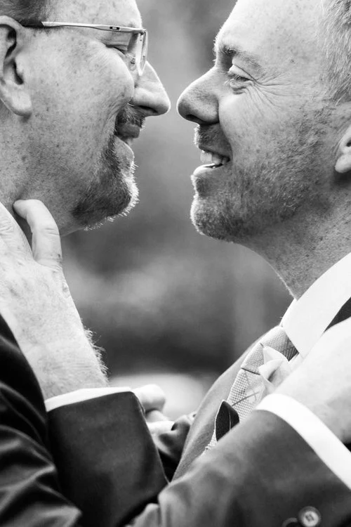 Two grooms leaning in for a kiss in black and white Missoula Montana Meera Graham Photography