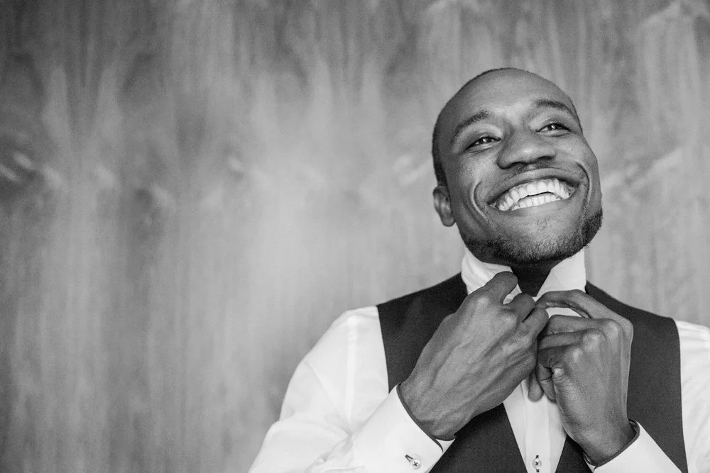 Groom smiling from ear to ear buttoning his shirt in Missoula MT Meera Graham Photography
