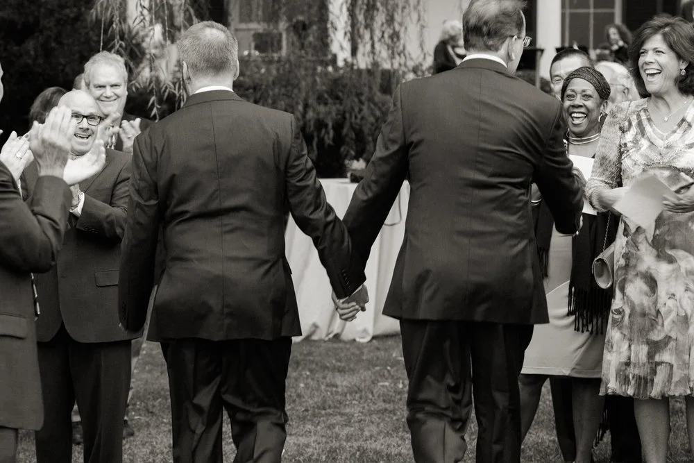 Newlywed grooms holding hands and walking back up the isle Montana Meera Graham Photography