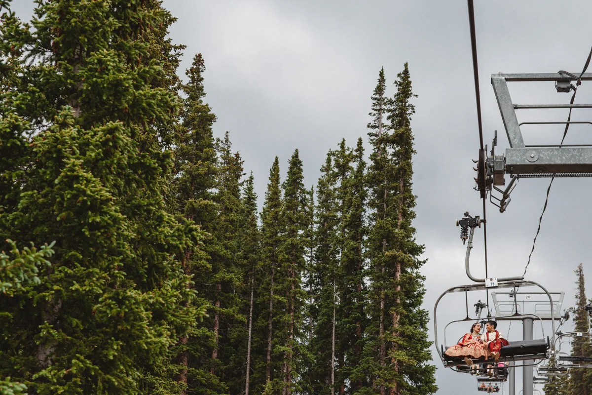 denver same-sex indian wedding couple on ski lift next to pine trees
