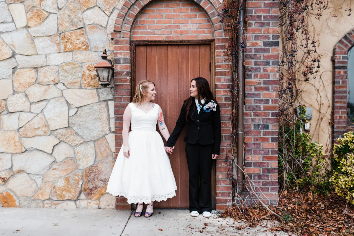 Rustic italian wedding couple holding hands in front of door