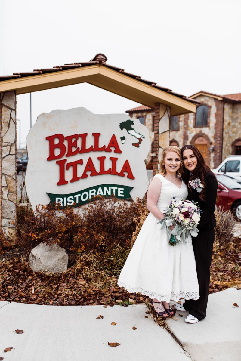 Rustic italian wedding couple in front of sign for bella italia