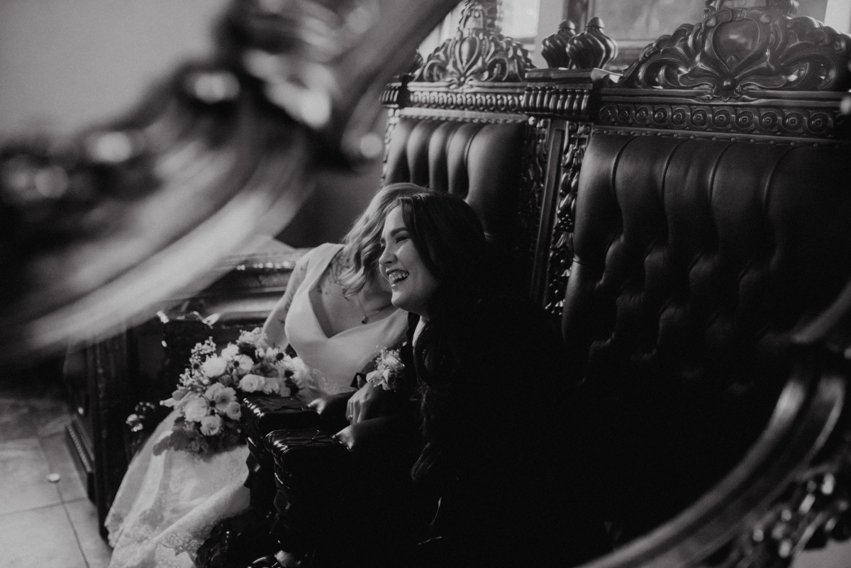 Rustic italian wedding couple laughing on high-backed chairs