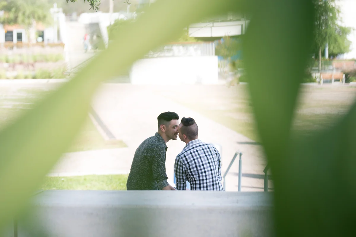 DOWNTOWN TAMPA ENGAGEMENT KISS SHOT THROUGH BUSH LEAVES