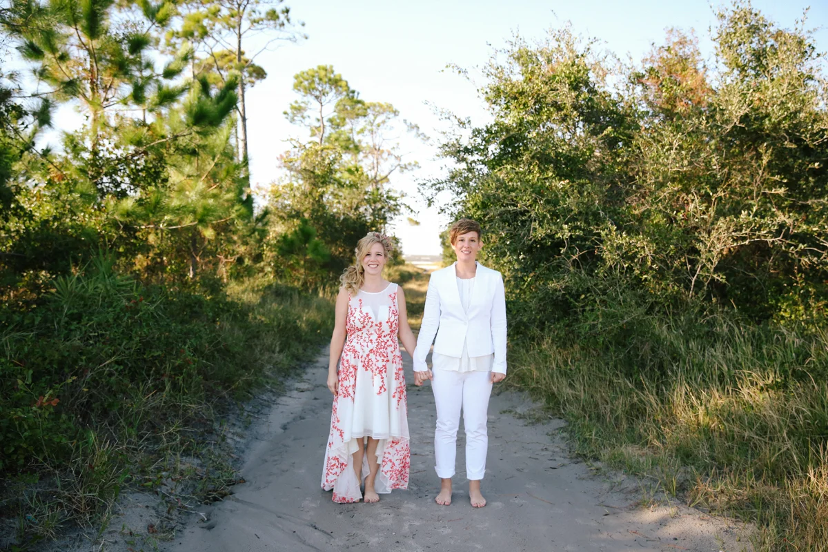 gulf shores destination wedding ajay and kate holding hands on tree-lined beach path