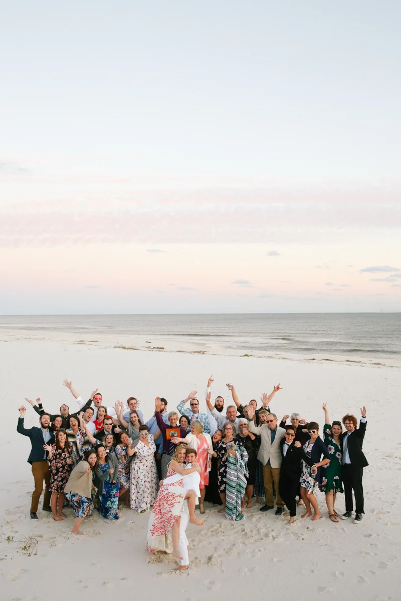 gulf shores destination wedding kate holding ajay in front while guests pose behind them