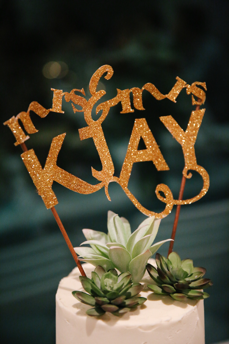 gulf shores destination wedding cake with glittery cake topper reading "mrs. and mrs. kjay"