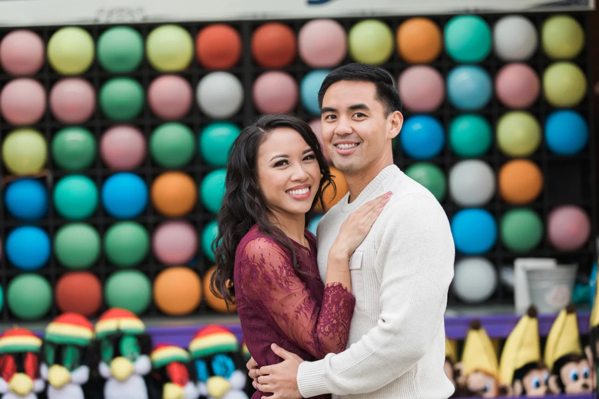 belmont park engagement session san diego embrace in front of darts game