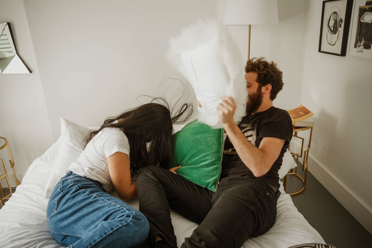 joshua tree california engagement session eda and matt on bed hitting each other with pillows