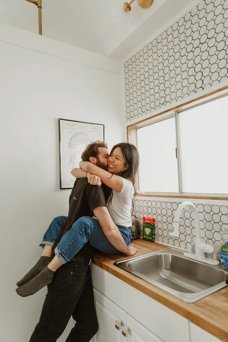 joshua tree california engagement session matt kissing eda's cheek, matt standing and eda sitting on kitchen counter