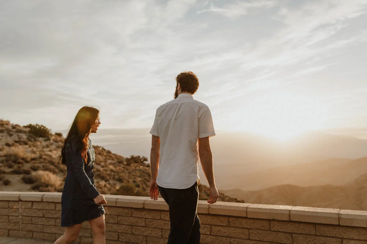 joshua tree california engagement session couple at brick wall facing sunset