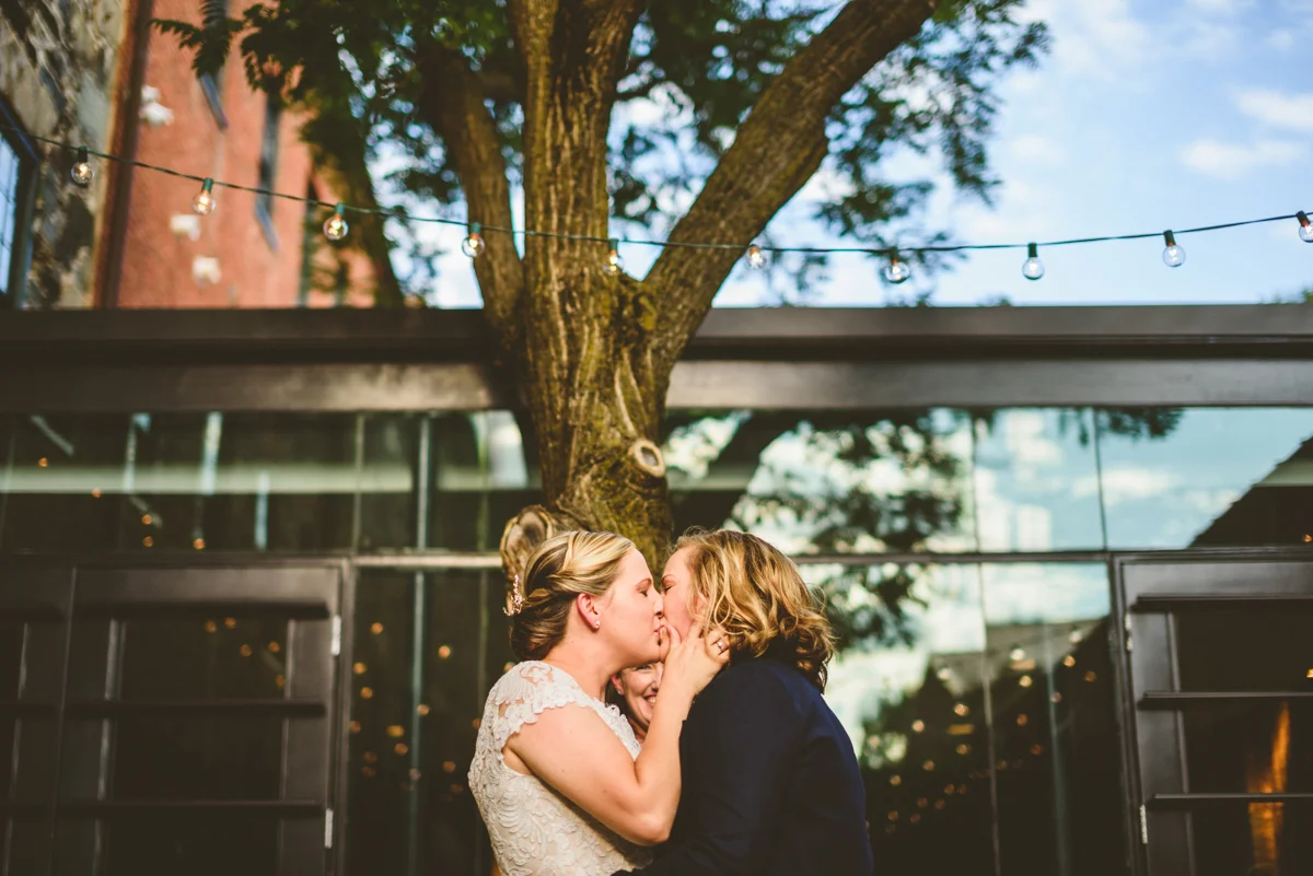 BALTIMORE WEDDING AT MOUNT WASHINGTON MILL DYE HOUSE KISS AT CEREMONY UNDER STRING LIGHTS