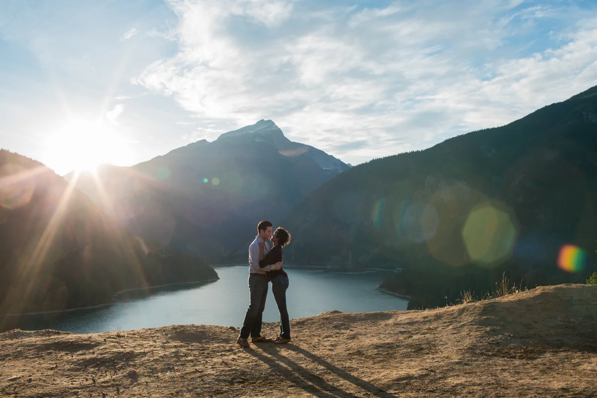 Diablo lake engagement session embrace overlooking mountain with sun setting