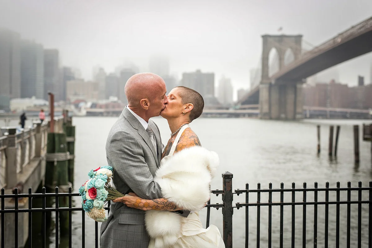 tattooed feminist elopement nyc kiss on boardwalk, river and bridge in background