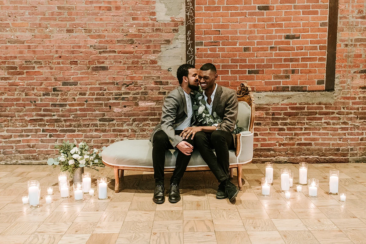 baltimore photo shoot couple on elegant couch with lit candles on floor, brick wall in background