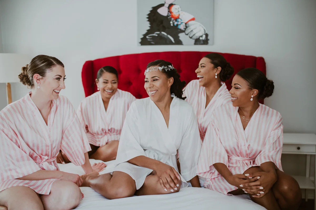 art-inspired levine museum wedding shavonne on bed laughing with bridesmaids