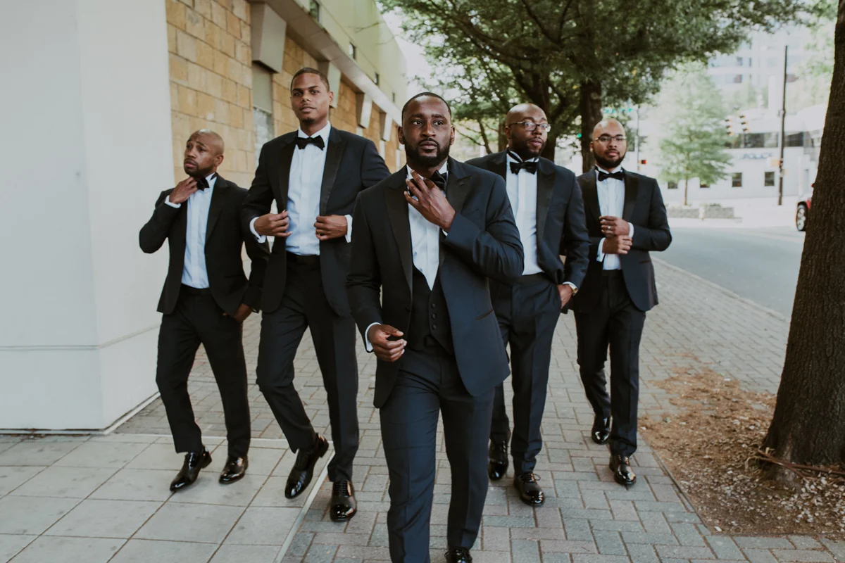 art-inspired levine museum wedding travis and groomsmen walking down sidewalk adjusting ties and jackets