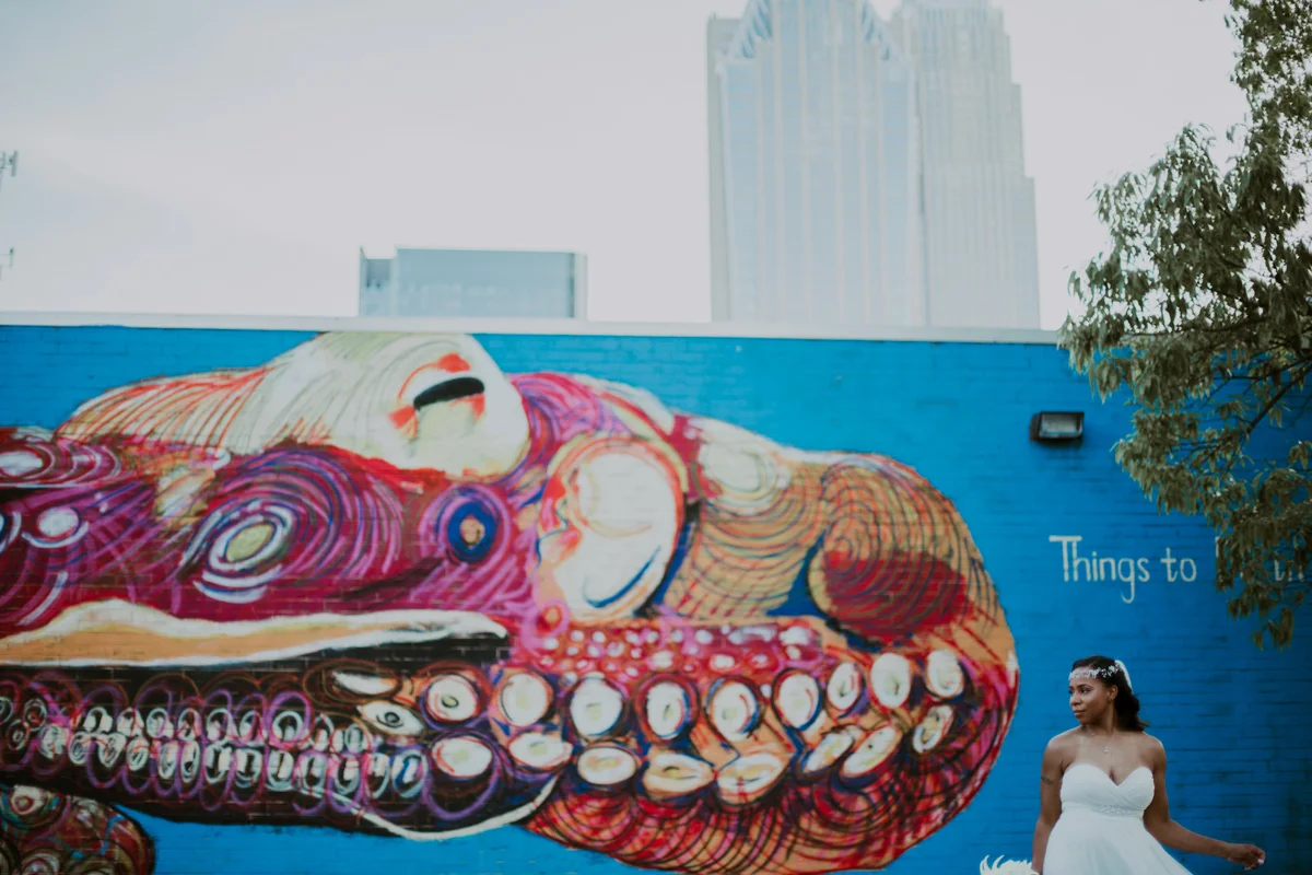 art-inspired levine museum wedding shavonne outside in front of mural wall