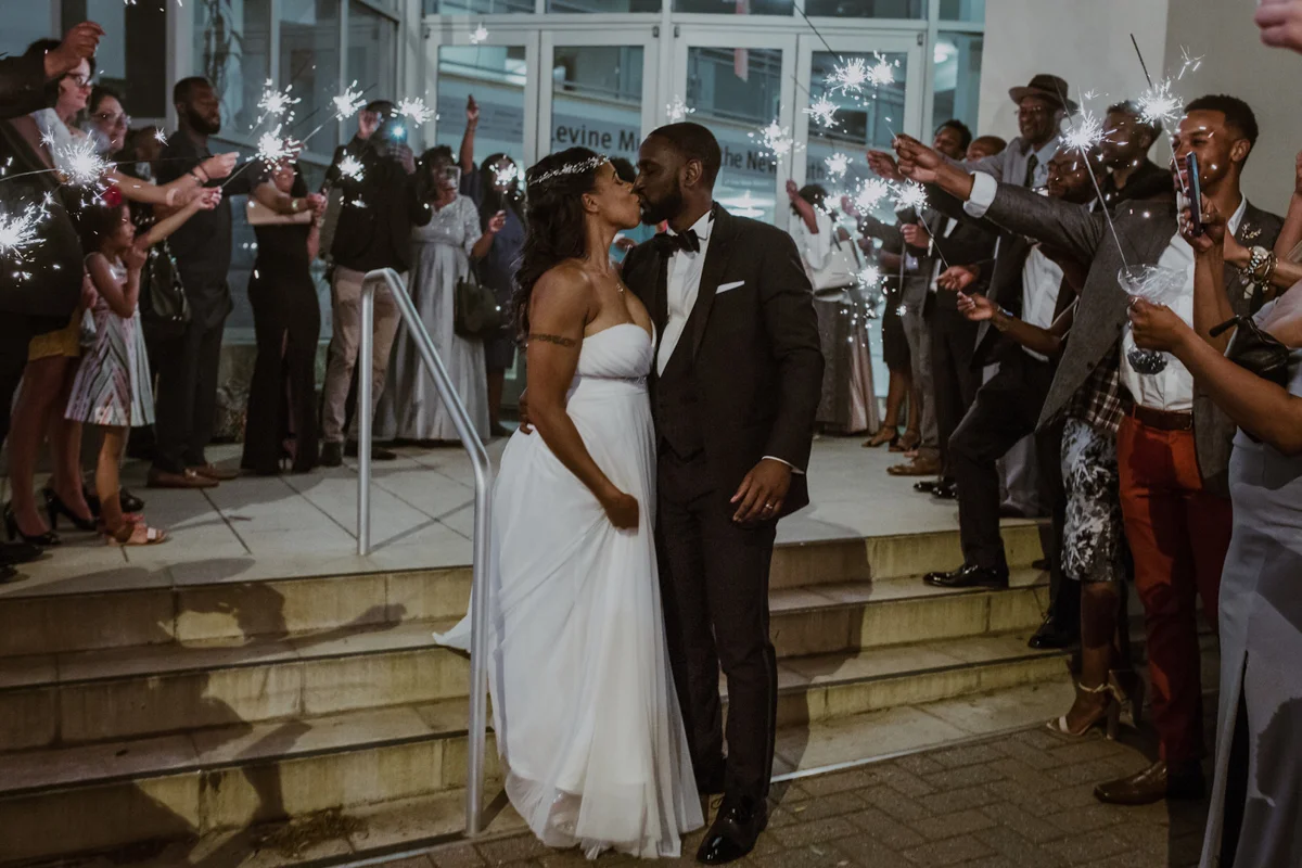 art-inspired levine museum wedding kiss outside museum while guests surround them with sparklers