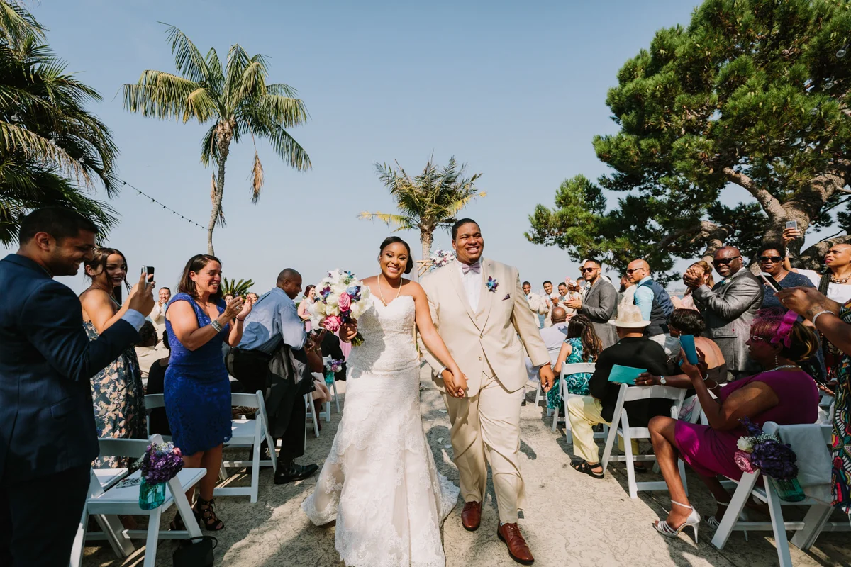 San Diego Tropical-Inspired Wedding newly married couple walking up aisle hand in hand as guests clap