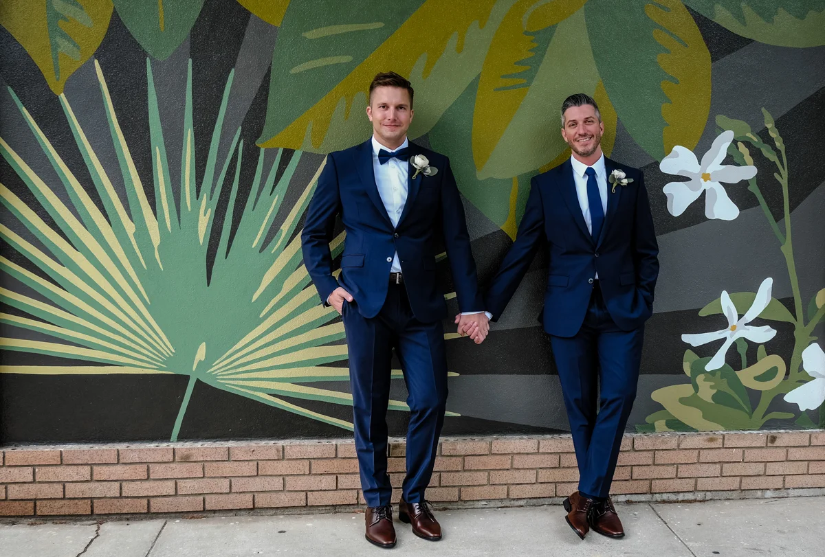 Classic southern style wedding savannah georgia couple holding hands in front of flora-themed mural