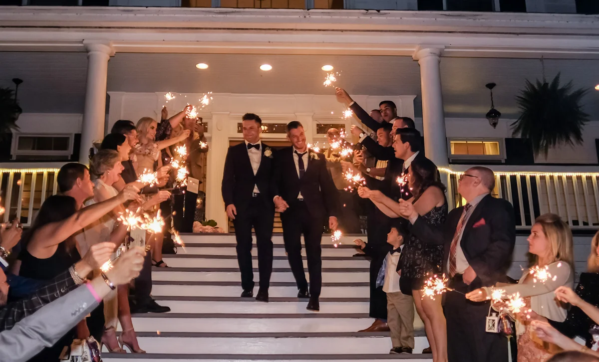 Classic southern style wedding savannah georgia grooms walking down porch steps with guests holding sparklers