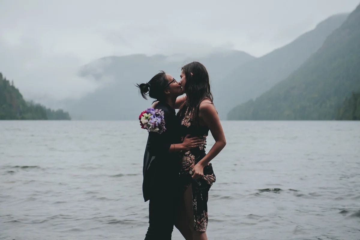 Cameron Lake Photo Session BC Canada camilla and ked kiss by foggy lake, mountains in the distance
