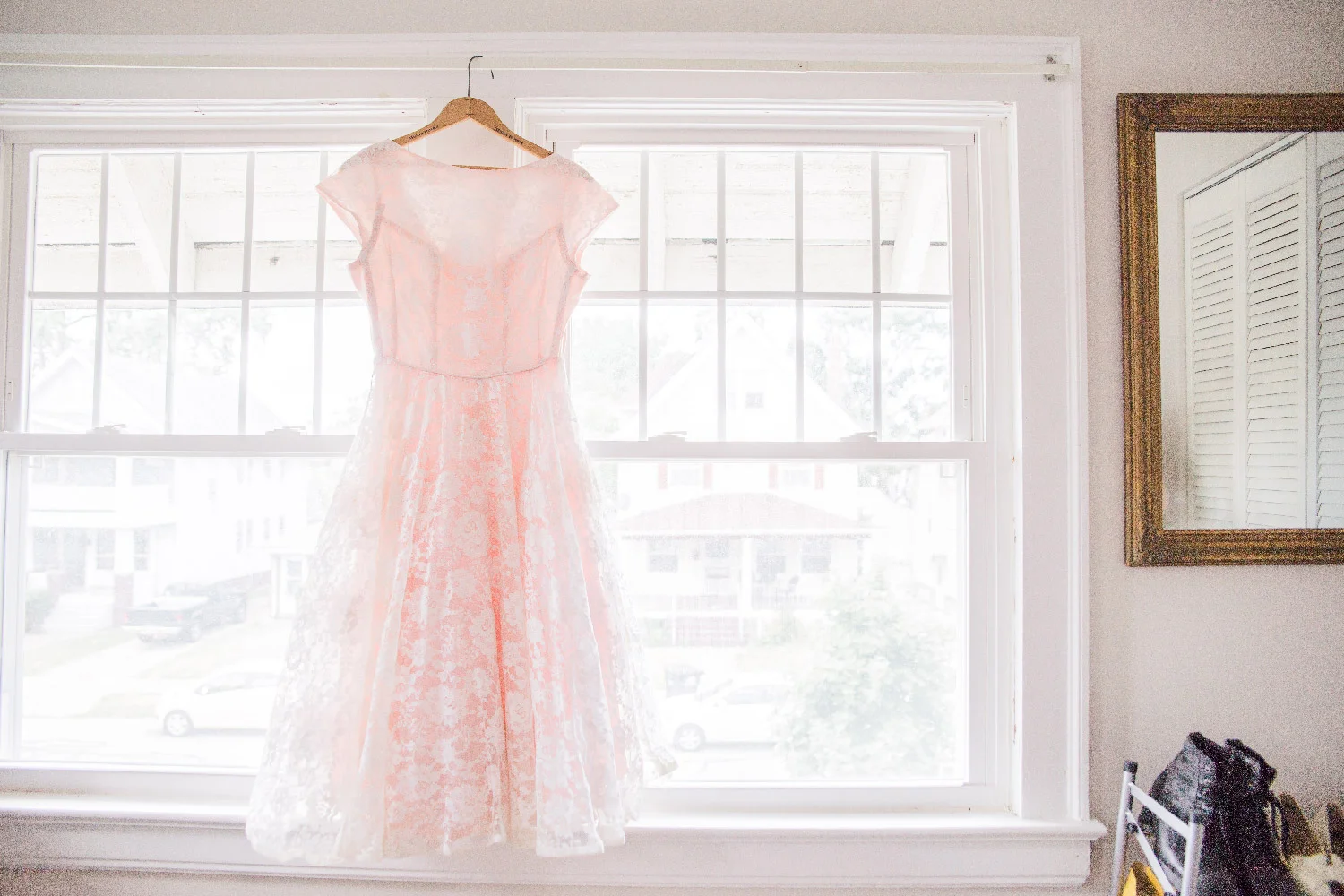 Bethany’s pink lace wedding dress hanging in window of their Cleveland Ohio home Lea Marie Photography