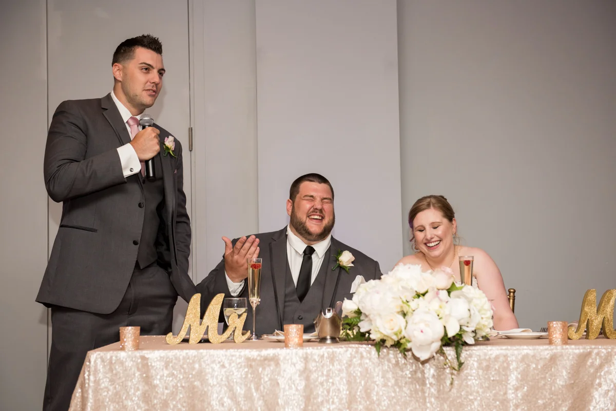 Newlywed couple sitting at their head table listening to a groomsman's speech Boston MA Leise Jones Photography